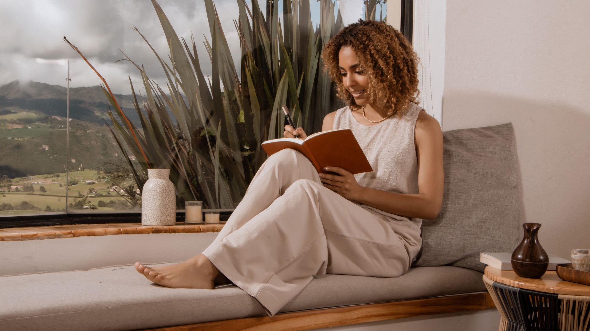 Woman writing in a notebook by a window