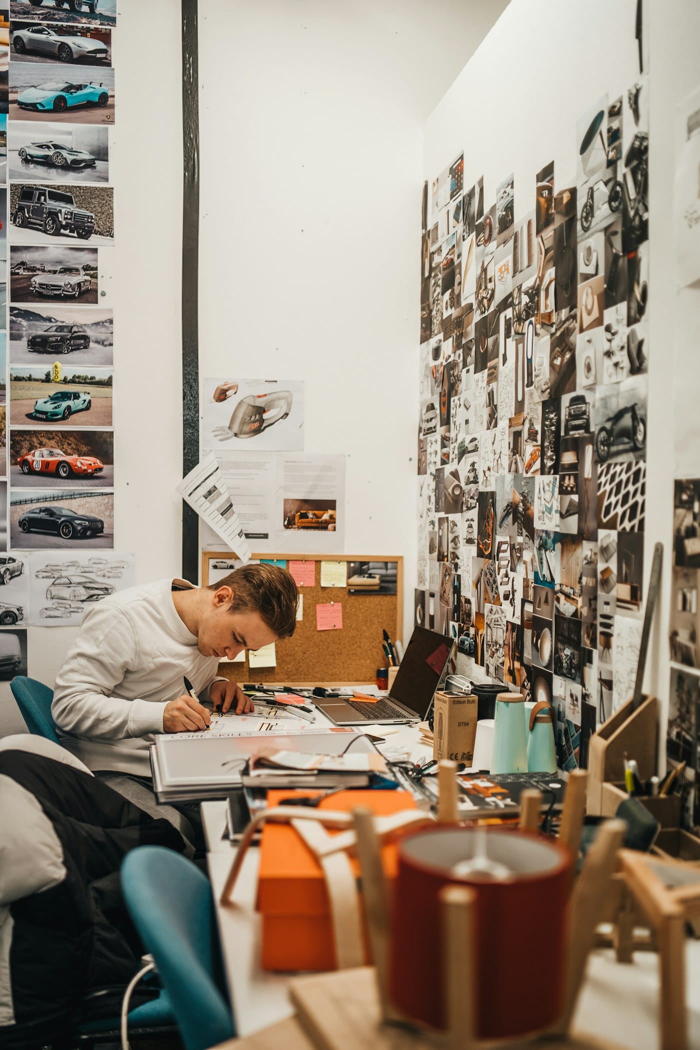 Man writing beside wall with car photos