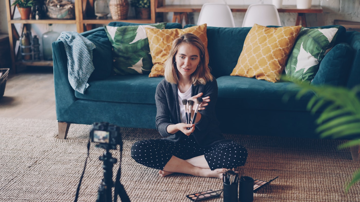 Woman filming herself with a camera in a living room