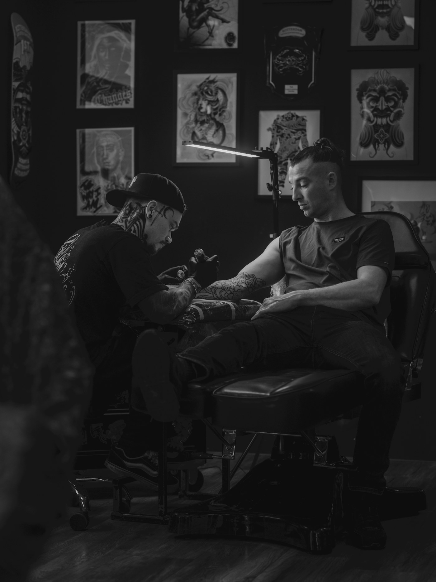 Tattoo artist working on a client's arm in studio