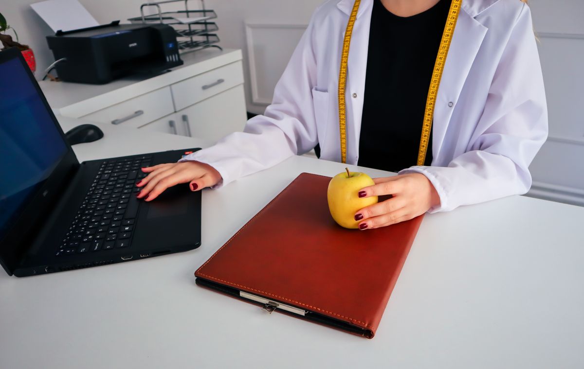 Nutritionist working at a desk with a laptop and fresh fruit