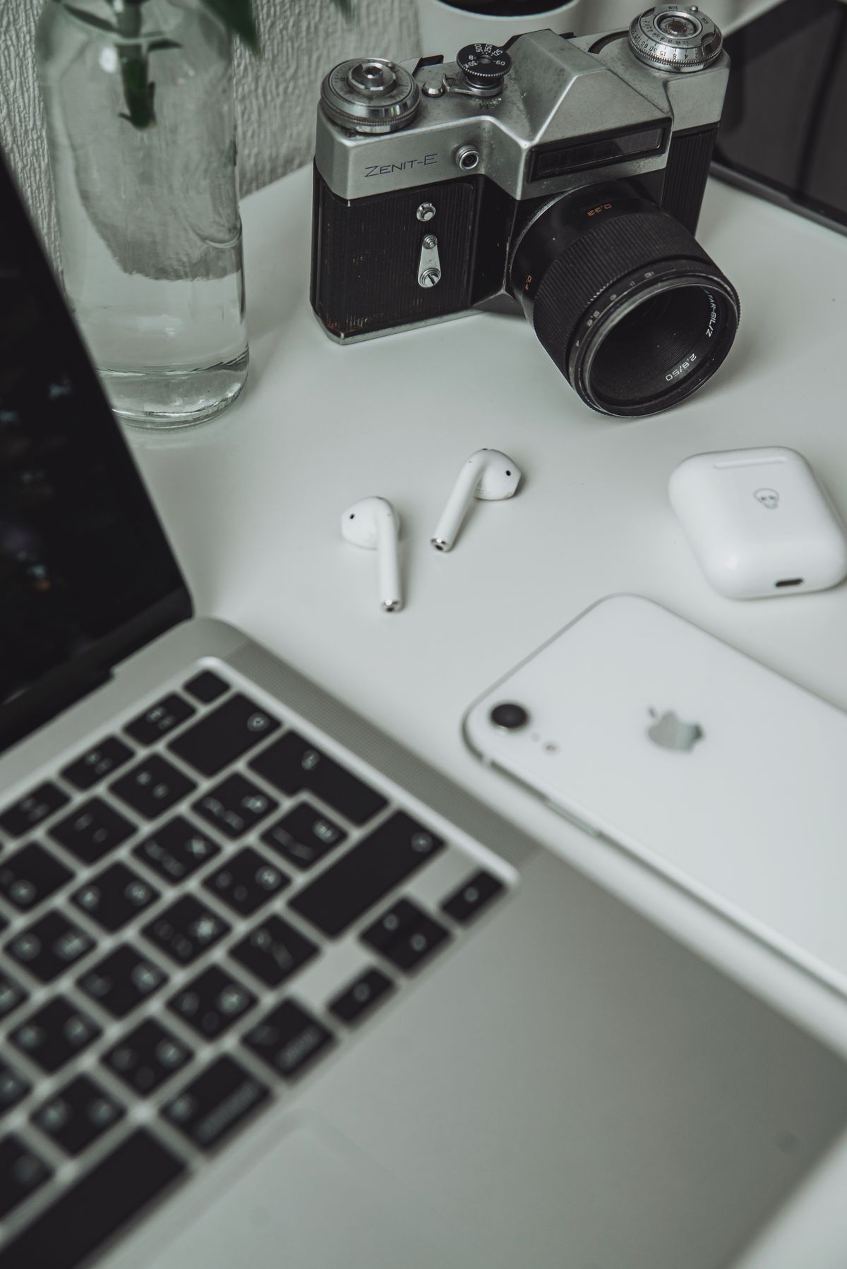 Technology review setup with a laptop, camera, phone, and earbuds